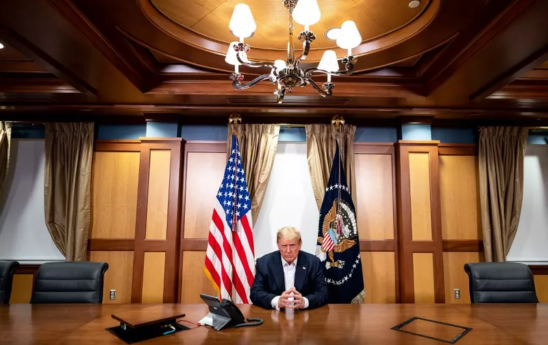 This handout photo released by the White House shows US President Donald Trump and his Chief of Staff (not pictured) participating in a phone call with the US Vice President, Secretary of State and Chairman of the Joint Chiefs of Staff on October 4, 2020, in his conference room at Walter Reed National Military Medical Center in Bethesda, Maryland. - President Donald Trump has "continued to improve" as he is treated for Covid-19 at a military hospital near Washington, his doctors said October 4, adding that he could be discharged as early as October 5. (Photo by Tia DUFOUR / The White House / AFP) / RESTRICTED TO EDITORIAL USE - MANDATORY CREDIT "AFP PHOTO / THE WHITE HOUSE / TIA DUFOUR " - NO MARKETING - NO ADVERTISING CAMPAIGNS - DISTRIBUTED AS A SERVICE TO CLIENTS