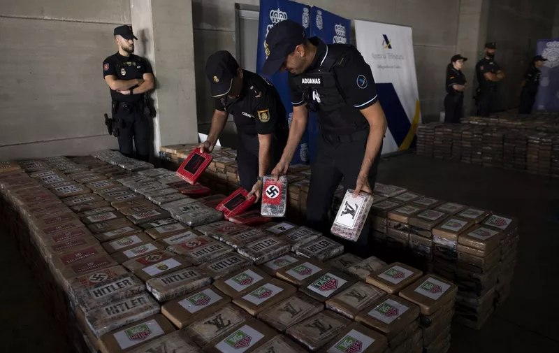 Spanish National Police and Customs officers hold some packages of cocaine totalizing 9,436 kilos, that were found hidden in a container from Ecuador, are seen during a police press conference at the port of Algeciras, southern Spain, on August 25, 2023. Spanish police and customs officials today announced the seizure of nearly 9.5 tonnes of cocaine from Ecuador, saying it marked Spain's biggest seizure to date. The seizure, which took place on August 23 in the southern port of Algeciras, is "the biggest cargo of cocaine in Spain to date" and was hidden in a refrigerated container coming from Ecuador among banana crates, according to a joint statement. (Photo by JORGE GUERRERO / AFP)