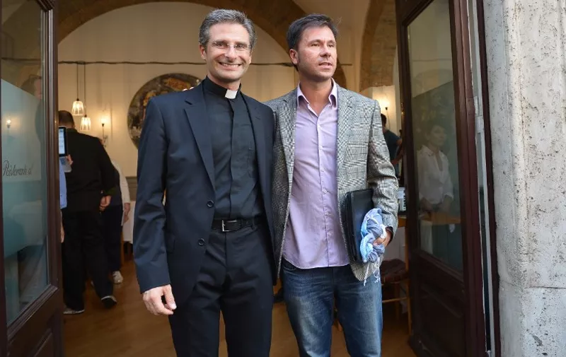 Father Krysztof Olaf Charamsa (L), who works for a Vatican office, poses with his partner Edouard after revealing his homosexuality during a press conference on October 3, 2015 in Rome. The priest said he wanted to challenge what he termed the Church's "paranoia" with regard to sexual minorities, claiming the Catholic clergy was largely made up of intensely homophobic homosexuals. The Vatican condemned the coming out of a Polish priest on the eve of a major synod as a "very serious and irresponsible," act which meant he would be stripped of his responsibilities in the Church's hierarchy. In a statement, a spokesman said Krzystof Charamsa would not be able to continue in his senior position in the Vatican and that his future as a priest would be decided by his local bishop.  AFP PHOTO / TIZIANA FABI