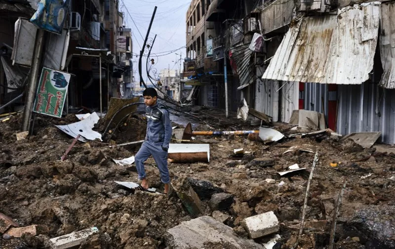 An Iraqi boy walks among debris on a street near Mosul's University on January 22, 2017, a week after Iraqi counter-terrorism service (CTS) retook it from the Islamic State (IS) jihadists. 
Iraqi forces battled the last holdout jihadists in east Mosul after commanders declared victory there and quickly set their sights on the city's west, where more tough fighting awaits. / AFP PHOTO / Dimitar DILKOFF
