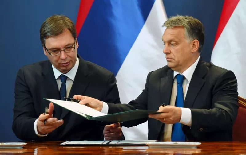 Serbian Prime Minister Aleksandar Vucic (L) and his Hungarian counterpart Victor Orban change their cooperation agreement in the Delegation Hall of the parliament building in the Hungarian capital Budapest on July 1, 2015. Vucic met his Hungarian counterpart Victor orban during a one-day official visit to the Hungarian capital to lead his delegation during a Hungarian-Serbian joint government meeting.  AFP PHOTO / ATTILA KISBENEDEK