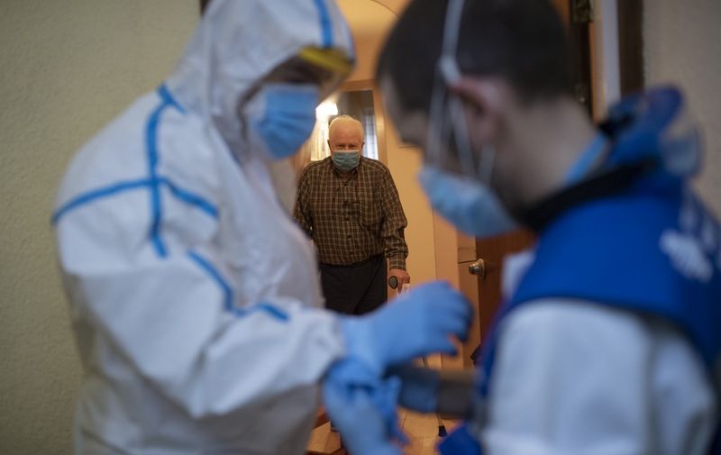 Member of the technical support team Joan Alcaraz (R) helps healthcare worker of the CAP Manso primary care centre, Kilian Trenard, to put his protective suit on before visiting a patient at his home in Barcelona on May 1, 2020. - Spain registered 281 deaths from coronavirus in the past 24 hours, bringing the total toll to 24,824, confirming the slowdown in the pandemic, according to figures released. (Photo by Josep LAGO / AFP)