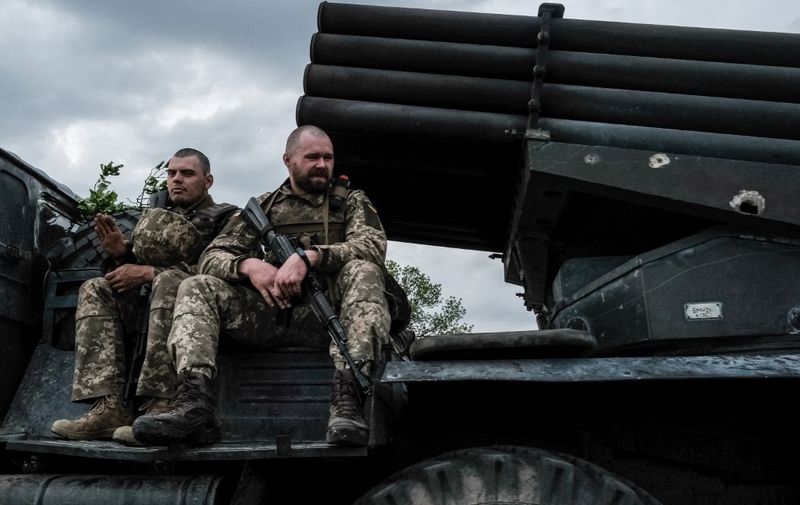 Ukrainian soldiers ride on a moving truck-mounted multiple rocket launcher near Lysychansk, eastern Ukraine on May 13, 2022. - More than six million refugees have fled Ukraine since Russia's invasion began on February 24, 2022, the UN refugee agency says. A total of 6,029,705 people had fled Ukraine as of May 11, with Poland hosting the largest number. Women and children represent 90 percent of the refugees. (Photo by Yasuyoshi CHIBA / AFP)