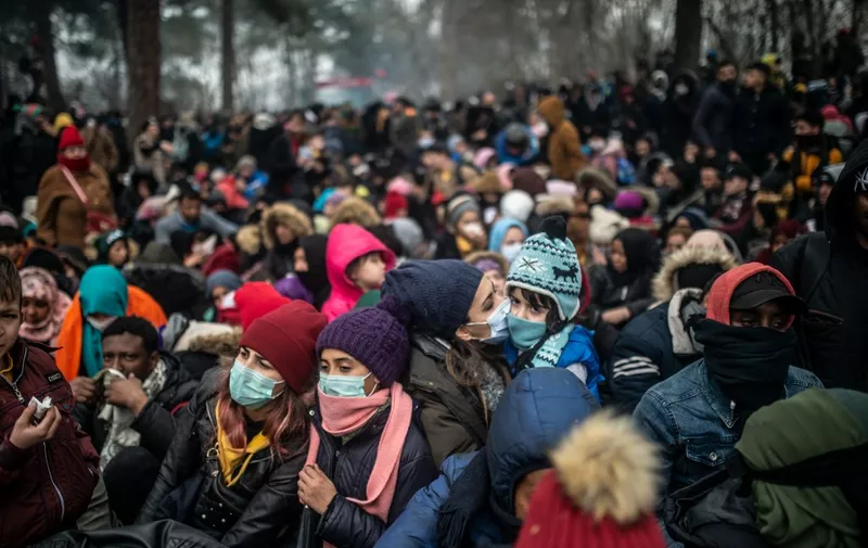 Migrants with protective masks wait at the buffer zone at Turkey-Greece border at Pazarkule, in Edirne district, on February 29, 2020. - Thousands of migrants stuck on the Turkey-Greece border clashed with Greek police on February 29, 2020, according to an AFP photographer at the scene. Greek police fired tear gas at migrants who have amassed at a border crossing in the western Turkish province of Edirne, some of whom responded by hurling stones at the officers. The clashes come as Greece bolsters its border after Ankara said it would no longer prevent refugees from crossing into Europe following the death of 33 Turkish troops in northern Syria. (Photo by BULENT KILIC / AFP)