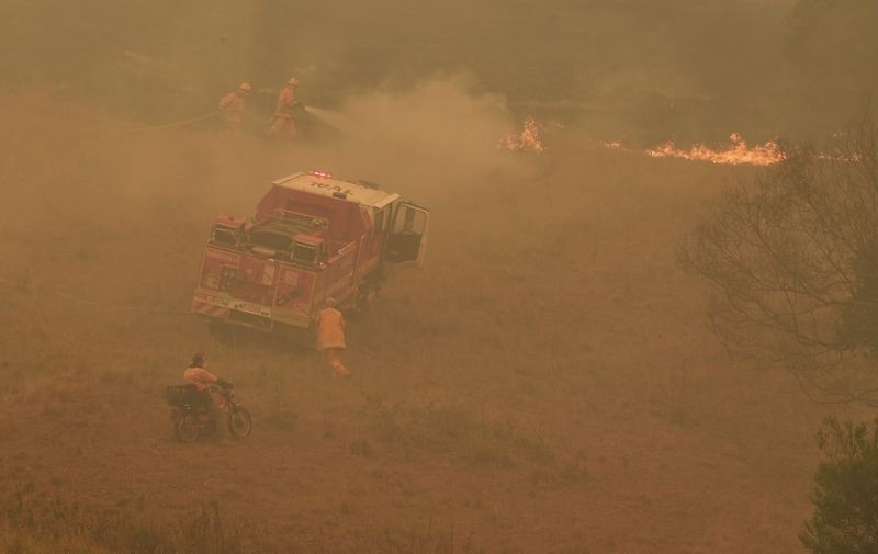 A farmer (bottom) watches as firefighters (top) put out flames near the town of Taree, some 350kms north of Sydney, on November 14, 2019. - The death toll from devastating bushfires in eastern Australia has risen to four after a man's body was discovered in a scorched area of bushland, police said on November 14. (Photo by WILLIAM WEST / AFP)