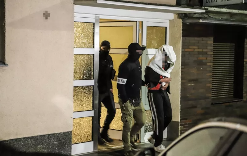 Police guide an arrested person out of a residential house in Hagen, western Germany, on May 3, 2023 as part of a "wide-scale" operation against the notorious Italian 'Ndrangheta mafia across Europe. - In Germany, hundreds of officers carried out raids in five parts of the country, regional prosecutors said in a statement, adding that operations also took place in Belgium, France, Italy, Portugal and Spain. (Photo by Alex Talash / AFP)
