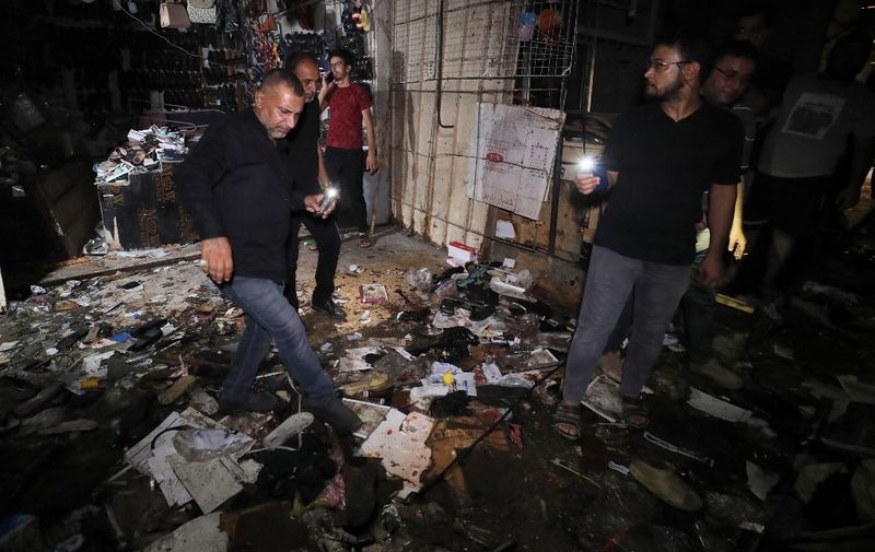 Iraqis inspect the site of the explosion in a popular market in the mostly Shiite neighbourhood of Sadr City, east of Baghdad, on July 19, 2021. - An explosion tore through the busy Baghdad market today killing at least 28 and wounding more than 50, in what Iraq says was a "terror attack" by an apparent suicide bomber. (Photo by AHMAD AL-RUBAYE / AFP)