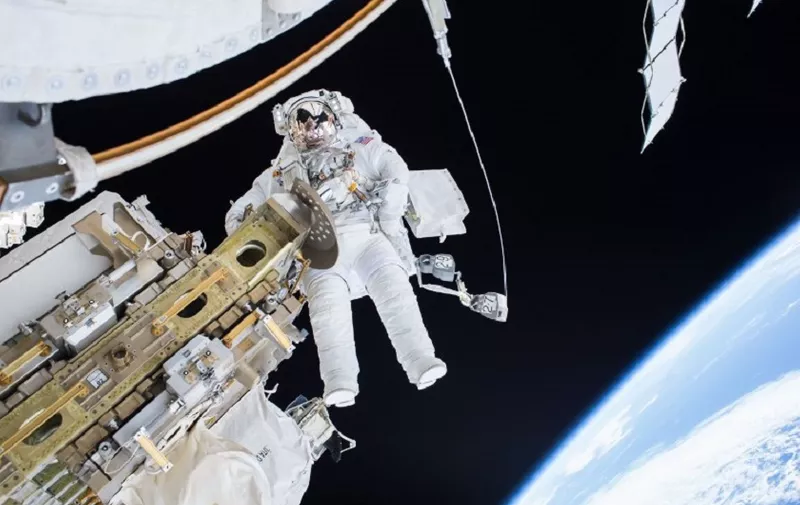 This NASA image released December 22, 2015 shows Expedition 46 Flight Engineer Tim Kopra on a December 21, 2015 spacewalk, in which Kopra and Expedition 46 Commander Scott Kelly successfully moved the International Space Station's mobile transporter rail car ahead of Wednesday's docking of a Russian cargo supply spacecraft. After quickly completing their primary objective for the spacewalk, Kelly and Kopra tackled several additional "get-ahead" tasks. Kelly routed a second pair of cables in preparation for International Docking Adapter installment work to support US commercial crew vehicles. Kopra routed an Ethernet cable that ultimately will connect to a Russian laboratory module. They also retrieved tools that had been in a toolbox on the outside of the station, so they can be used for future work. The three-hour and 16-minute spacewalk was the second for Kopra, who arrived to the station on Dec. 15, and the third for Kelly, who is nine months into a yearlong mission. AFP PHOTO/NASA = RESTRICTED TO EDITORIAL USE - MANDATORY CREDIT "AFP PHOTO / NASA" - NO MARKETING NO ADVERTISING CAMPAIGNS - DISTRIBUTED AS A SERVICE TO CLIENTS = (Photo by HO / NASA / AFP)