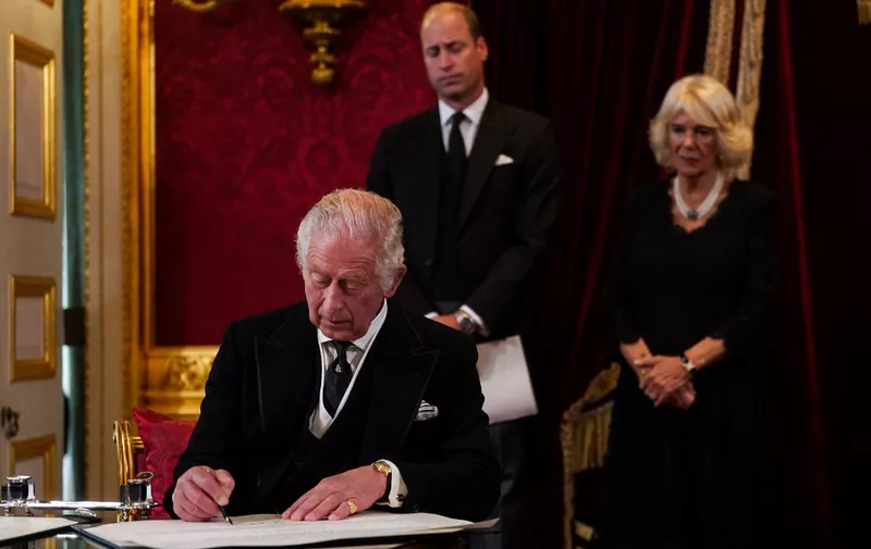 Britain's Prince William, Prince of Wales (C) and Britain's Camilla, Queen Consort (R) watch as Britain's King Charles III signs an oath to uphold the security of the Church in Scotland, during a meeting of the Accession Council inside St James's Palace in London on September 10, 2022, to proclaim him as the new King. - Britain's Charles III was officially proclaimed King in a ceremony on Saturday, a day after he vowed in his first speech to mourning subjects that he would emulate his "darling mama", Queen Elizabeth II who died on September 8. (Photo by Victoria Jones / POOL / AFP)