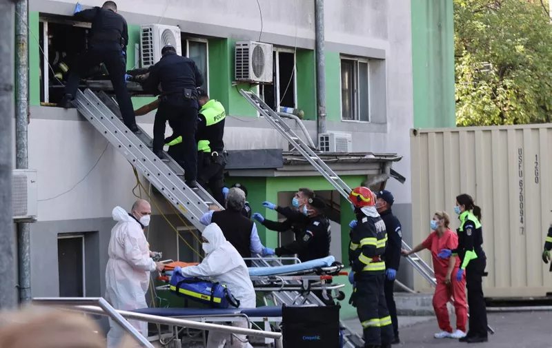 Firemen and policemen evacuate a burned victim from the infectious diseases hospital in Constanta, Romania, on October 1, 2021, after a fire broke out in the intensive care unit where ten Covid patients were being treated. - Several patients of Covid-19 died on october 1, 2021 in the fire of a hospital in Constanta (south-eastern Romania), according to the inspectorate for emergencies (ISU). It's the third tragedy of this type recorded in less than a year in this country with dilapidated infrastructures. Five patients died in January in a fire that ravaged a Bucharest hospital, two months later another disaster killed 15 patients in a hospital in Piatra Neamt (north-east). (Photo by Costin Dinca / AFP)