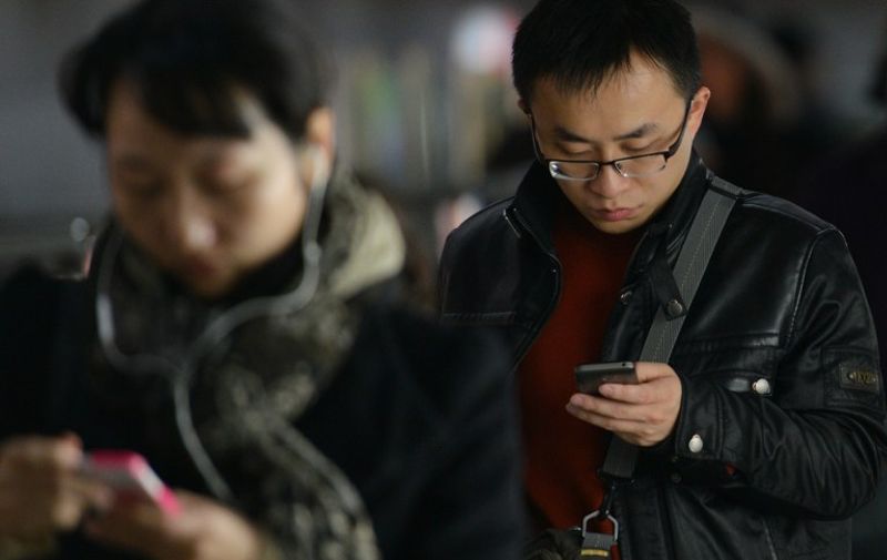 TO GO WITH China-IT-telecommunication-Tencent,FOCUS BY AMANDA WANG
People use their mobile devices in a metro station in Shanghai on March 12, 2014. WeChat has taken China by storm in just three years, allowing its more than 300 million users to send text, photos, videos and voice messages over smartphones, find each other by shaking their devices -- a common dating technique -- and even book and pay for taxis. AFP PHOTO/Peter PARKS / AFP PHOTO / PETER PARKS