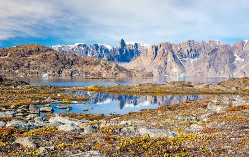 Reflection in a small lake surrounded by autumn-colored tundra of a mountain landscape in Scoresby Sound, Greenland (Photo by Raphaël Sane / Biosphoto / Biosphoto via AFP)