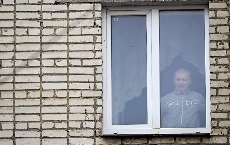 Alexei Moskalyov, 54, a single parent of Maria Moskalyova, the 13-year-old girl who drew a picture critical of Moscow's military campaign in Ukraine at school in April last year, looks out through the window of his flat after he was placed under house for repeating Ukraine posts discrediting the Russian army, in the town of Yefremov in the Tula region on March 23, 2023. In the Russian town of Yefremov, residents say they are shocked by the case of a father separated from his 13-year-old daughter because of her drawing criticising Moscow's offensive. (Photo by Natalia KOLESNIKOVA / AFP)