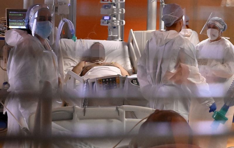 Medical staff members stand near a patient at Covid-19 intensive care unit (ICU) at The Institute of Clinical Cardiology (ICC) in Rome, on December 30, 2021. (Photo by Alberto PIZZOLI / AFP)