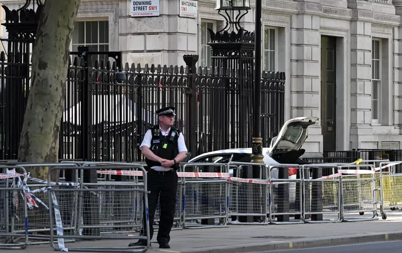 A police officer stands guard near to a car, seen at the gates of Downing Street, on Whitehall in central London on May 25, 2023, after crashing into the front gates of Downing Street, the official residence of Britain's Prime Minister. Armed police arrested one man after a car crashed into the gates of the UK prime minister's Downing Street residence in central London on Thursday, Scotland Yard said. (Photo by JUSTIN TALLIS / AFP)