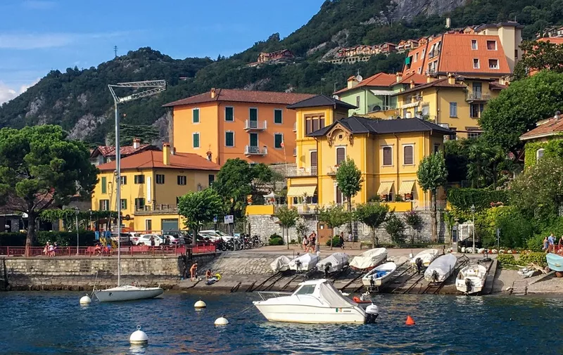A photo taken on August 19, 2020 shows boats and houses in the city of Varenna, on Lake Como in Lombardy. - Venice has turned into a ghost town, the jet-set resort of Portofino on the Ligurian coast is deserted, as is Varenna on the shores of Lake Como: tourism in Italy, the world's fifth-largest destination, is paying a heavy price to the coronavirus pandemic. (Photo by Brigitte HAGEMANN / AFP)