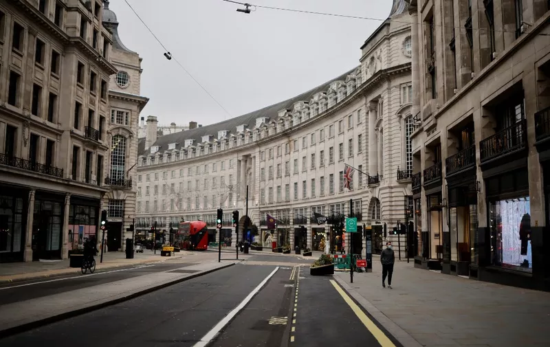 A man wearing a facemask walks along a near-deserted Regent Street, central London on January 8, 2021, as England entered a third lockdown due to the novel coronavirus Covid-19. - Faced by a sharp rise in coronavirus infections, driven by the new strain, England entered a strict lockdown on January 5, 2021, with schools and non-essential shops closed for at least six weeks after previous measures failed to halt the steep rise in cases. (Photo by Tolga Akmen / AFP)