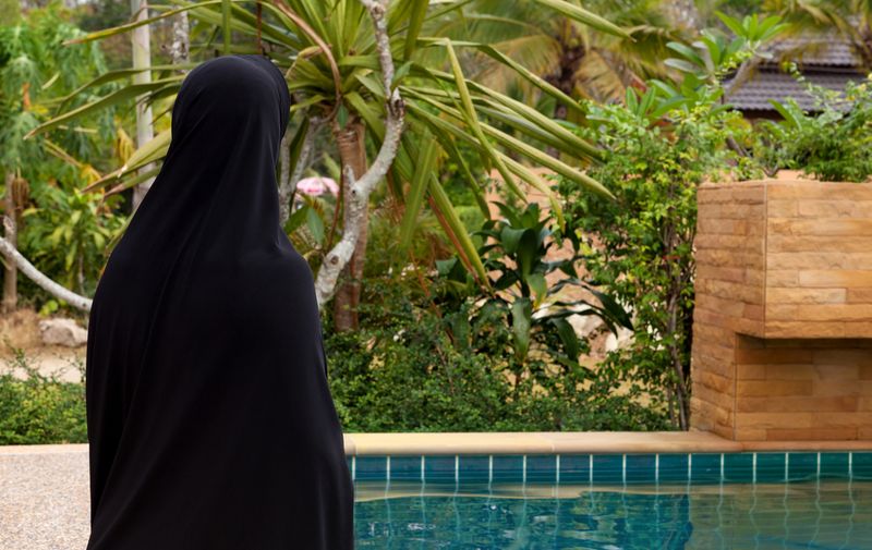 Arabic woman with black hijab or burka headscarf at pool in luxurious tropical resort.,Image: 389656710, License: Royalty-free, Restrictions: , Model Release: yes, Credit line: Profimedia