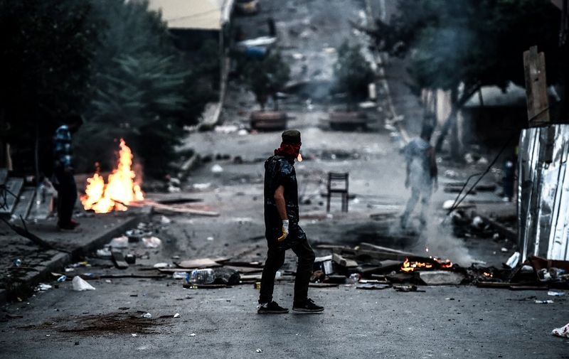 A left-wing protester waits in front of a barricade during clashes with Turkish riot police in the district of Gazi in Istanbul, on July 26, 2015. A Turkish policeman was killed on July 26, 2015 during clashes with protesters in the flashpoint Istanbul district of Gazi which have raged for the last three days following the death of a leftist activist during raids by the security forces. Turkey has launched a two-pronged "anti-terror" cross-border offensive against Islamic State (IS) jihadists and Kurdistan Workers Party (PKK) militants after a wave of violence in the country, pounding their positions with air strikes and artillery. But the expansion of the campaign to include not just IS targets in Syria but PKK rebels in neighbouring northern Iraq -- themselves bitterly opposed to the jihadists -- has put in jeopardy a truce with the Kurdish militants that has largely held since 2013. AFP PHOTO / OZAN KOSE (Photo by OZAN KOSE / AFP)