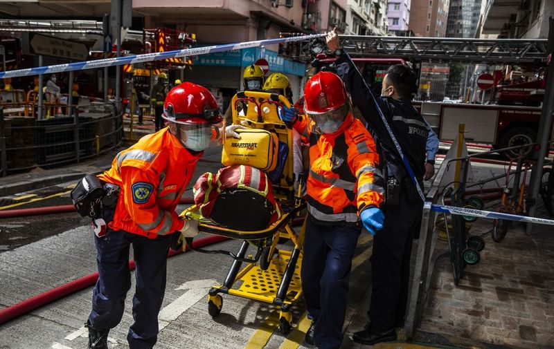 Ambulance officers rush a man (C) to a hospital who was burnt in an apartment fire in the Wan Chai district of Hong Kong on December 18, 2020. (Photo by ISAAC LAWRENCE / AFP)