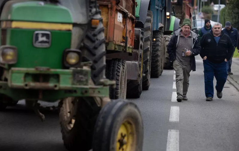 Farmers walk past tractors as they are blocked by French gendarmerie during a gathering  as part of the nationwide protests of farmers against agricultural policies in Guingamp, western France, on February 20, 2024. Farmers across Europe have staged protests in recent weeks over shrinking incomes, rising costs and what they say are increasingly onerous environmental rules approved by the 27-nation EU. (Photo by FRED TANNEAU / AFP)