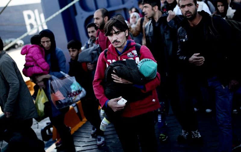 Migrants and refugees disembark from a government-chartered ferry at the Greek port of Piraeus, about 12 kilometres (7 miles) from central Athens, on October 25, 2015. An unprecedented 670,000 people mainly fleeing conflict in Syria, Iraq and Afghanistan have flooded into Europe so far this year, in the biggest movement of its kind since World War II.  AFP PHOTO / ANGELOS TZORTZINIS