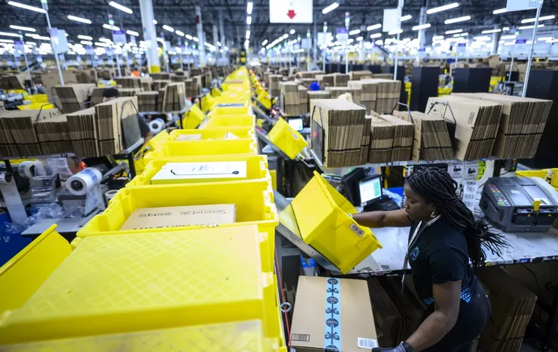 A woman works at a packing station at the 855,000-square-foot Amazon fulfillment center in Staten Island, one of the five boroughs of New York City, on February 5, 2019. - Inside a huge warehouse on Staten Island thousands of robots are busy distributing thousands of items sold by the giant of online sales, Amazon. (Photo by Johannes EISELE / AFP)