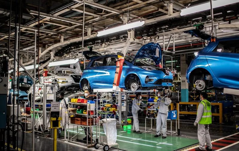 Employees wearing protective masks against the spread of the novel coronavirus, COVID-19, work along the assembly line that produces both the electric vehicle Renault Zoe and the hybrid vehicle Nissan Micra, at Flins-sur-Seine, the largest Renault production site in France on May 6, 2020. To reopen following the March 17th lockdown across France, the factory has had to enforce all the safety measure required to reduce any spread of COVID-19 at the assembly plant, with workers having to wear protective masks and gloves and diving the assembly line into individual parts to spot any person-to-person contamination. (Photo by Martin BUREAU / AFP)