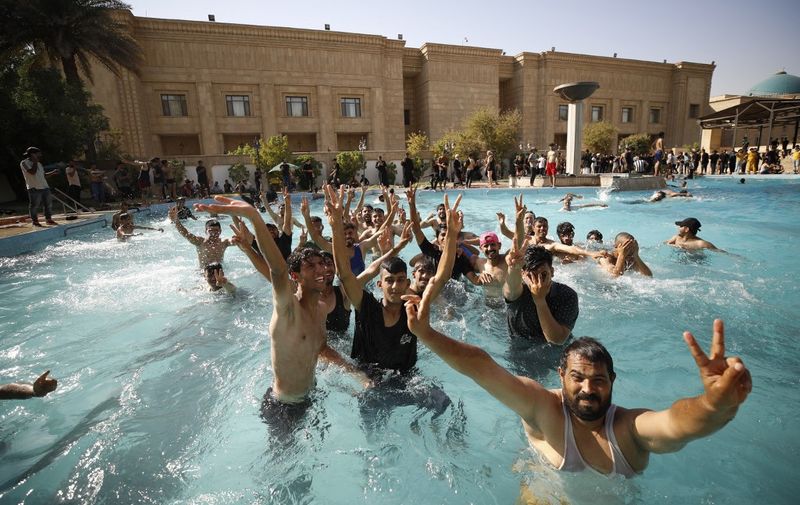 Supporters of Iraqi Shiite cleric Moqtada Sadr swim in the pool of the Government Headquarters in the capital Baghdad's Green Zone, on August 29, 2022. - Dozens of angry supporters of the powerful cleric stormed the Republican Palace, a ceremonial building in the fortified Green Zone, a security source said, shortly after Sadr said he was quitting politics. The army has announced a  Baghdad-wide curfew to start from 3:30 pm (1230 GMT). (Photo by Ahmad Al-rubaye / AFP)