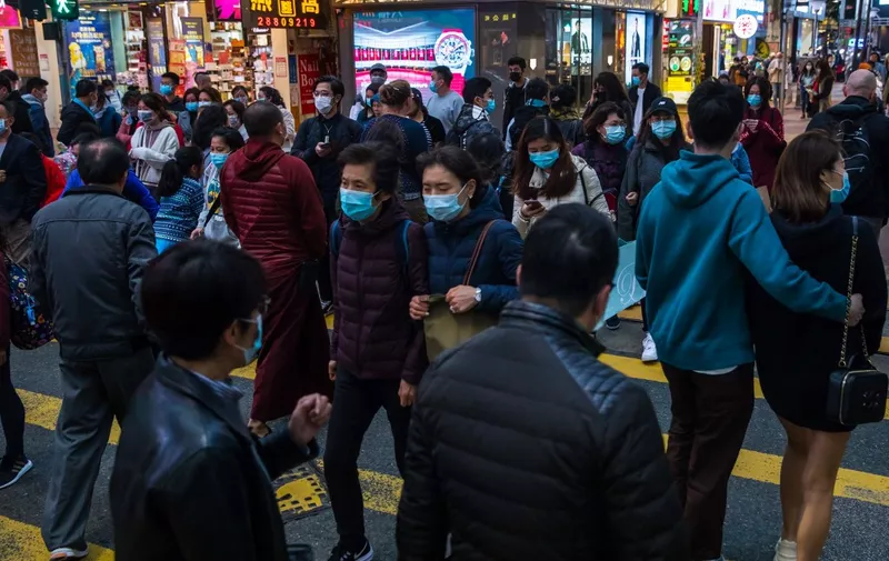 People wearing masks cross a street in a shopping district in Hong Kong on January 26, 2020, as a preventative measure following a coronavirus outbreak which began in the Chinese city of Wuhan. - Hong Kong on January 25 declared a new coronavirus outbreak as an "emergency" -- the city's highest warning tier -- as authorities ramped up measures to reduce the risk of further infections. (Photo by DALE DE LA REY / AFP)