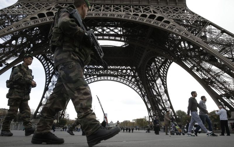 Soldiers patrol at the foot of the Eiffel Tower in Paris on November 16, 2015 three days after the terrorist attacks that left at least 129 dead and more than 350 injured. France prepared to fall silent at noon on November 16 to mourn victims of the Paris attacks after its warplanes pounded the Syrian stronghold of Islamic State, the jihadist group that has claimed responsibility for the slaughter. AFP PHOTO / KENZO TRIBOUILLARD / AFP / KENZO TRIBOUILLARD