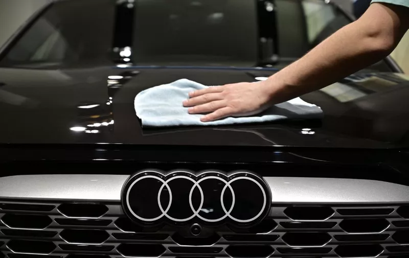 The Audi logo is seen as a worker polishes an Audi Q8 55 e-tron quattro car on the sidelines of the annual press conference of German car giant Volkswagen (VW) to present the business report, on March 14, 2023 in Berlin. Volkswagen is planning to invest 122 billion euros ($130 billion) in the shift towards electric vehicles over the coming years, as the battle for dominance in the EV market heats up. (Photo by John MACDOUGALL / AFP)