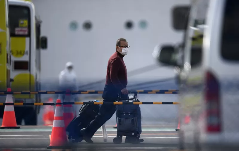 A passenger leaves after disembarking from the Diamond Princess cruise ship - in quarantine due to fears of the new COVID-19 coronavirus - at the Daikoku Pier Cruise Terminal in Yokohama on February 19, 2020. - Relieved passengers began leaving a coronavirus-wracked cruise ship in Japan on February 19 after testing negative for the disease that has now claimed more than 2,000 lives in China. (Photo by CHARLY TRIBALLEAU / AFP)