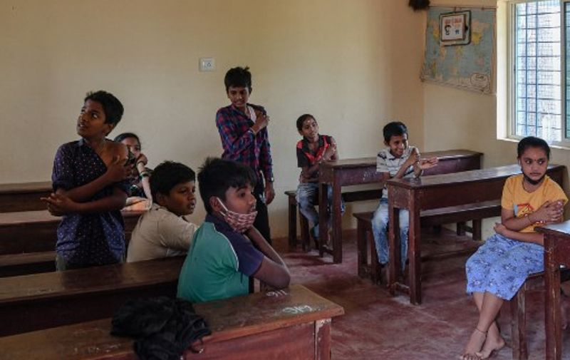 School students inoculated with a dose of Corbevax vaccine wait inside a classroom for observation, during a vaccination drive held for children in the age group of 12-14, as a preventive measure against Covid-19 coronavirus disease in Bangalore on March 30, 2022. (Photo by Manjunath Kiran / AFP)