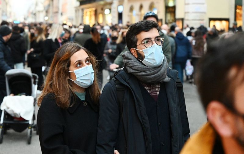People wear protective face masks as they walk along the Via del Corso main shopping street in central Rome on December 05, 2021, as the city brought the obligation through December 04-31 to wear masks outdoors in the city centre and other busy shopping areas, in a bid to reduce the risk of covid infections among the crowds of people during the Christmas season. (Photo by Vincenzo PINTO / AFP)