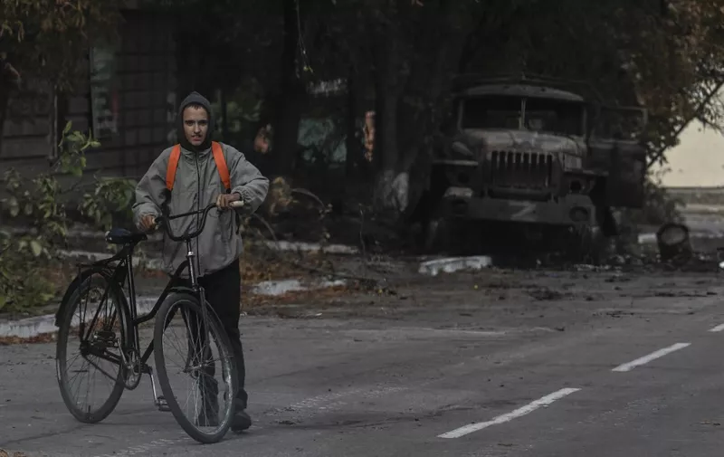 A man with a bicycle walks past a destroyed military vehicle in Balakliya, Kharkiv region, on September 10, 2022. - Ukrainian forces said September 10, 2022 they had entered the town of Kupiansk in eastern Ukraine, dislodging Russian troops from a key logistics hub in a lightning counter-offensive that has seen swathes of territory recaptured. (Photo by Juan BARRETO / AFP)