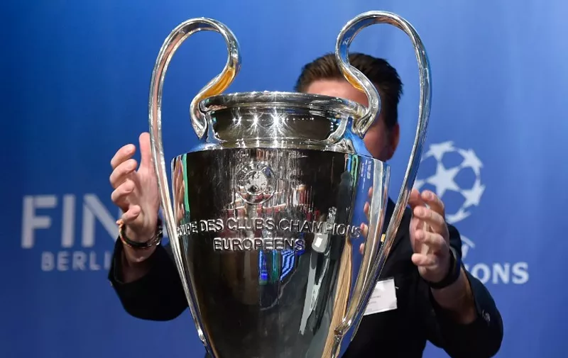 A UEFA logistics employee brings the UEFA Champions League trophy on stage prior to the draw for the UEFA Champions League semi-final football matches at the UEFA headquarters in Nyon on April 24, 2015. AFP PHOTO / FABRICE COFFRINI