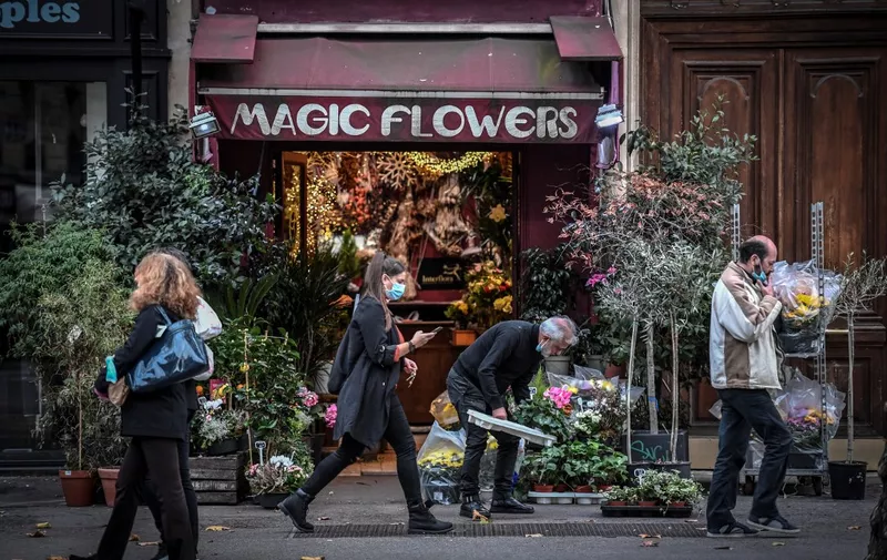 A woman, wearing a face mask, walks in front of a flower shop on October 31, 2020 in Paris on the second day of a second national general lockdown decided by the French government to contain the spread of Covid-19 outbreak due to the novel coronavirus. - French President announced on October 28, 2020 a new lockdown aimed at halting an alarming acceleration of Covid-19 cases, to take effect from October 30 until "at least December 1". (Photo by STEPHANE DE SAKUTIN / AFP)