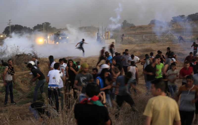Palestinian protestors run for cover from tear gas fired by Israeli security forces during clashes after the demonstrators tore down a section of a border fence between Israel and the central Gaza Strip east of Bureij on October 13, 2015. The outbreak of violence between Palestinians, Israeli forces and Jewish settlers in recent weeks has worsened in October, raising fears of a third intifada, or uprising. AFP PHOTO / MOHAMMED ABED