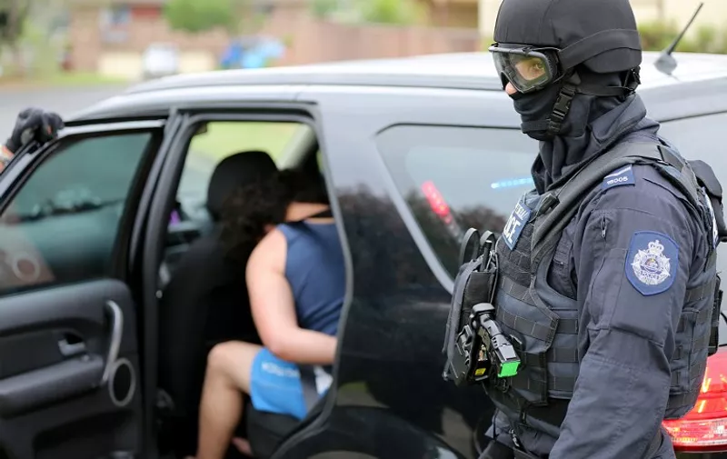 This handout photo taken and released by the New South Wales Police on December 10, 2015 shows a man (L) being arrested during a counter-terrorism operation in Sydney. Two people, including a 15-year-old boy, were arrested on December 10 in Sydney over a terror plot targeting a government building, with authorities expressing alarm at the age of those being radicalised. AFP PHOTO / NEW SOUTH WALES POLICE -----EDITORS NOTE---- RESTRICTED TO EDITORIAL USE - MANDATORY CREDIT "AFP PHOTO / NEW SOUTH WALES POLICE" - NO MARKETING NO ADVERTISING CAMPAIGNS - DISTRIBUTED AS A SERVICE TO CLIENTS / AFP / NEW SOUTH WALES POLICE / NEW SOUTH WALES POLICE