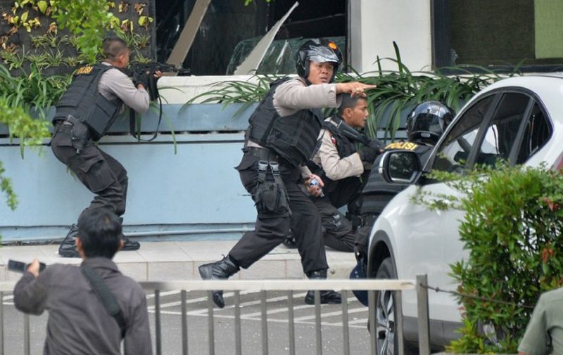 Indonesian police take position and aim their weapons as they pursue suspects outside a cafe after a series of blasts hit the Indonesia capital Jakarta on January 14, 2016. A series of bombs killed at least three people in the Indonesian capital Jakarta on January 14, with shots fired outside a cafe as police moved in, an AFP journalist at the scene said.     AFP PHOTO / Bay ISMOYO / AFP / BAY ISMOYO