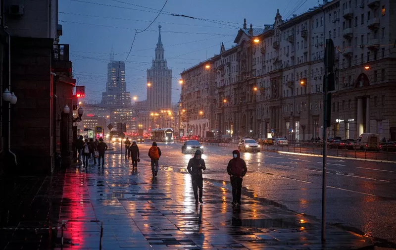 People walk down a street during a storm in Moscow on November 30, 2021. (Photo by DIMITAR DILKOFF / AFP)