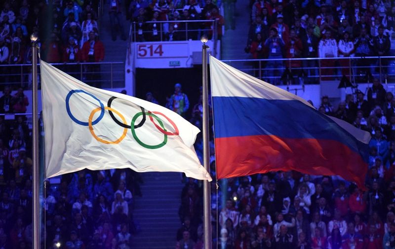 The Olympic flag (L) and the Russian flag flutter during the Closing Ceremony of the Sochi Winter Olympics at the Fisht Olympic Stadium on February 23, 2014.   AFP PHOTO / DAMIEN MEYER (Photo by Damien MEYER / AFP)