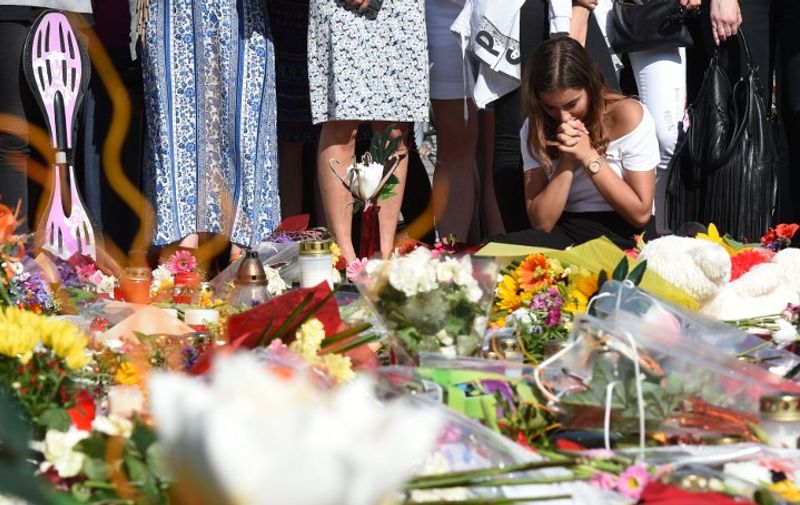 A woman mourns in front of candles and flowers on July 24, 2016 in front of the Olympia Einkaufszentrum shopping centre in Munich, southern Germany, where an 18-year-old German-Iranian student run amok. 
Europe reacted in shock to the third attack on the continent in just over a week, after David Ali Sonboly went on a shooting spree at a shopping centre on July 22, 2016 in what appears to have been a premeditated attack, before turning the gun on himself. / AFP PHOTO / Christof Stache