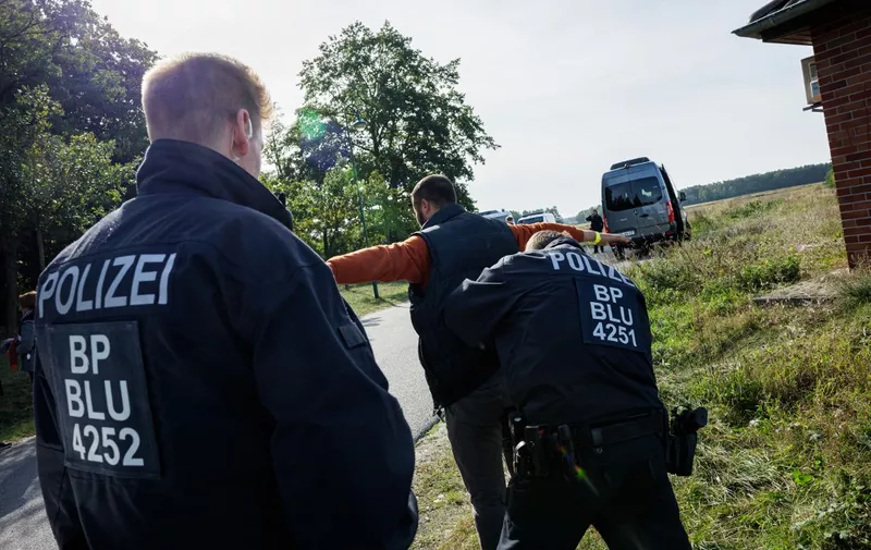 Officers of the German Federal Police (Bundespolizei) check a migrant near Forst, eastern Germany on October 11, 2023, during a patrol near the border with Poland. (Photo by JENS SCHLUETER / AFP)