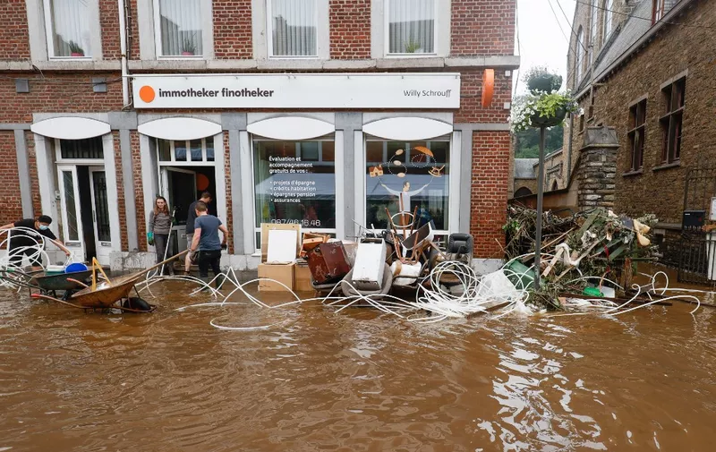 Local residents clear up a shop during the flood in Pepinster on July 16, 2021 as the situation remains critical as the water keep rising after the heavy rainfall of the previous days. - The death toll from devastating floods in Europe soared to at least 126 on July 16, 2021, most in western Germany where emergency responders were frantically searching for missing people. In Belgium, the government confirmed the death toll had jumped to 20 -- earlier reports had said 23 dead -- with more than 21,000 people left without electricity in one region. (Photo by BRUNO FAHY / BELGA / AFP) / Belgium OUT