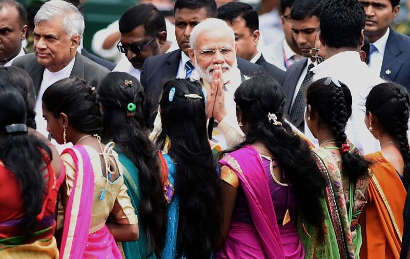 India's Prime Minister Narendra Modi (C) gestures to bystanders as he arrives with arrives with Sri Lankan Prime Minister Ranil Wickremesinghe (L) to address a public rally in the tea-growing town of Norwood, some 80kms east of Colombo on May 12, 2017.
Indian Prime Minister Narendra Modi declared that his desire for a "quantum jump" in relations with Sri Lanka, as New Delhi jostles with regional rival Beijing for influence in the island nation. / AFP PHOTO / Ishara S. KODIKARA
