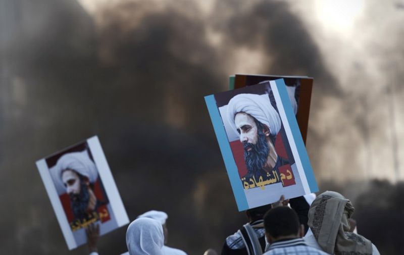 Bahraini protesters hold placards bearing portraits of prominent Shiite Muslim cleric Nimr al-Nimr during clashes with riot police in the village of Sitra, south of the capital Manama, on January 8, 2016, following a protest against his execution by Saudi authorities. Nimr was a driving force of the protests that broke out in 2011 in the kingdom's east, an oil-rich region where the Shiite minority of an estimated two million people complains of marginalisation. / AFP / MOHAMMED AL-SHAIKH
