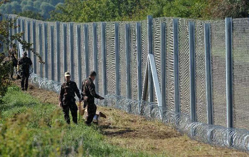 Hungarian soldier are seen as they work on reinforcing the fence along the borderline with Croatia, just meters away from border crossing in Baranjsko Petrovo Selo, near north eastern Croatian town of Beli Manastir, on October 1, 2015. The recently installed fence along border with Croatia is being reinforced with razor wire as Hungary is considering closing down it's frontier with Croatia in order to keep of thousands of Middle Eastern migrants on the move towards Western European countries. AFP PHOTO ELVIS BARUKCIC