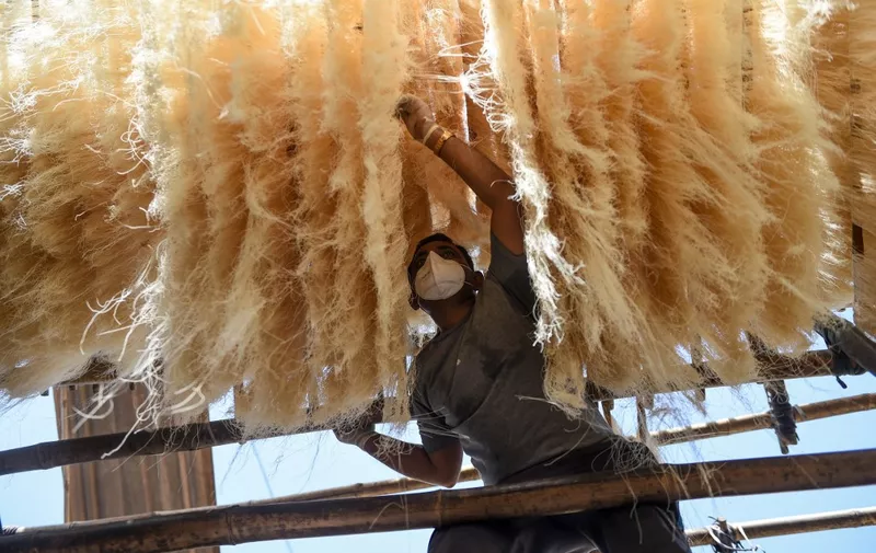 The owner of the workshop, Jamilbhai Ansari, wearing a facemask and hand gloves dries vermicelli in Ahmedabad on May 23, 2020. (Photo by SAM PANTHAKY / AFP)